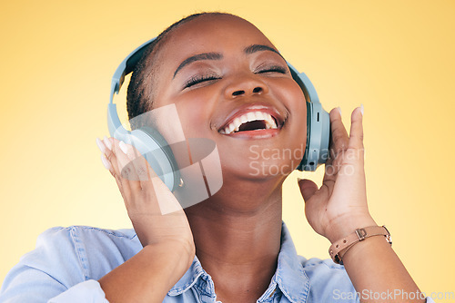 Image of Singing, music and black woman on headphones, happy and listening in studio isolated on a yellow background. Smile, radio and African person streaming podcast, audio and sound, hearing and freedom.