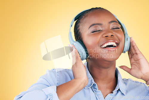 Image of Singer, music and black woman on headphones, smile and listening in studio isolated on a yellow background. Excited, radio and African person streaming podcast, audio and sound, hearing and freedom.