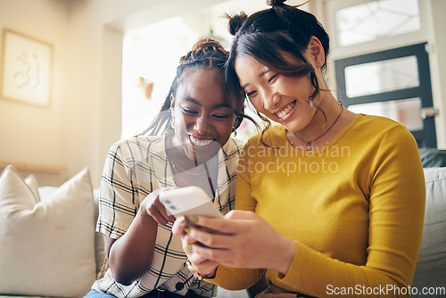 Image of Young women, funny meme and smartphone, friends relax at home with social media and communication. Gen z, happiness and comedy online, chat and using phone with people on couch, mobile app and tech