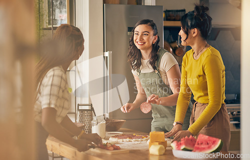 Image of Happy, friends and women cooking pizza in kitchen, bonding and having fun together in home. Smile, girls and baking food, margherita and salami bread at lunch, cheese on meat and watermelon at brunch