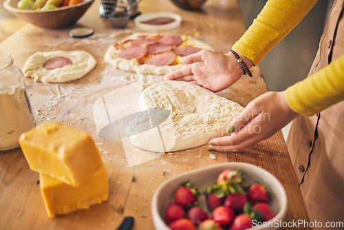 Image of Pizza, heart with dough and hands on wooden table, person cooking with flour and cheese, fruit and food at home. Nutrition, meal and strawberry in kitchen, baking with ingredients and love sign