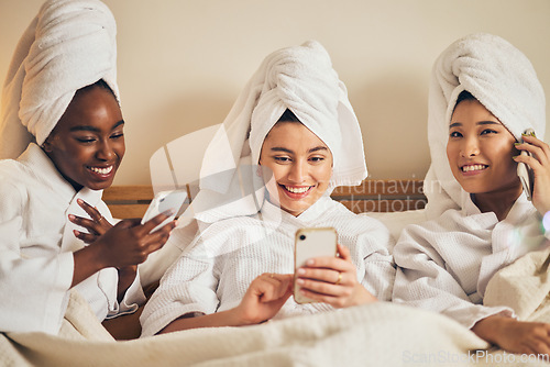 Image of Spa day, sleepover and friends with phone in bed relax with social media during beauty routine at home. Happy, self care and women in bedroom with smartphone for internet, search or diy skincare idea