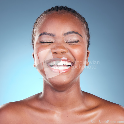 Image of Beauty, skincare facial and black woman with laughing, cosmetics and makeup in studio. Wellness, African female model and joke with blue background and skin glow with shine from dermatology treatment