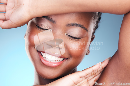 Image of Beauty, skincare and black woman closeup of armpit and smile, cosmetics and makeup in studio. Wellness, happy African model on blue background and skin glow with shine from dermatology treatment