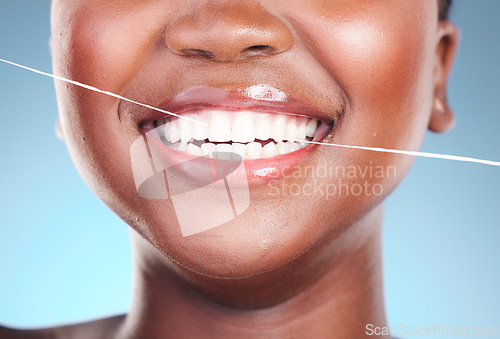 Image of Happy woman, teeth and dental floss in cleaning, hygiene or cosmetics against a blue studio background. Closeup of female person with big smile flossing in tooth whitening for oral, mouth or gum care