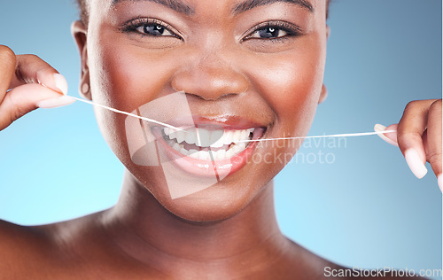 Image of Happy woman, teeth and dental floss in cleaning, grooming or skincare against a blue studio background. Closeup of female person with big smile flossing in tooth whitening for oral, mouth or gum care