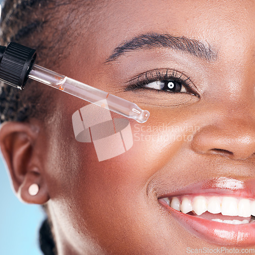 Image of Beauty, face and happy black woman with serum skin hydration, anti aging or collagen oil for studio skincare treatment. Retinol dropper, hyaluronic acid or closeup African person on blue background