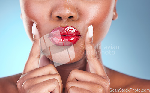 Image of Woman, kiss and red lipstick, beauty and makeup closeup with hands on face isolated on blue background. Model, bold and cosmetic product on lips, lipgloss and mouth with skin and shine in studio