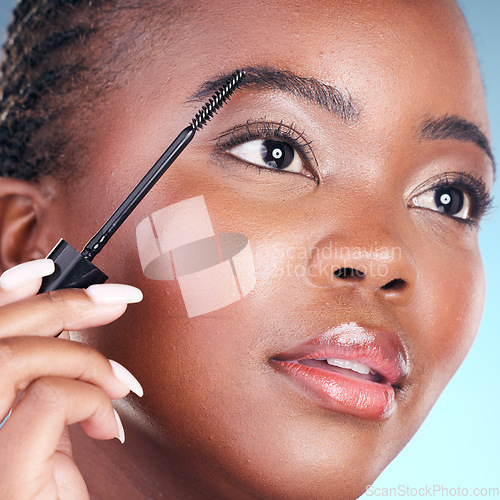 Image of Studio face, black woman and eyebrow mascara, product or cosmetology tools for facial cosmetics application. Beauty routine, brow care makeup and closeup African person on blue background