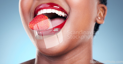 Image of Woman, eating and strawberry, red lipstick and beauty, makeup closeup isolated on blue background. Fruit, healthy and model in a studio with bold cosmetic product, mouth and cosmetology with shine