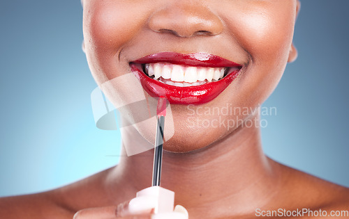 Image of Woman, smile and red lipstick with brush and beauty, happy with makeup closeup isolated on blue background. Model, bold and cosmetic product on lips, mouth with skin and teeth with shine in studio