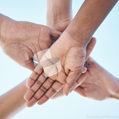 Image of Blue sky, hands stack and together for team building motivation, group cooperation or community goals support. Closeup below view, synergy commitment and people collaboration, teamwork and solidarity