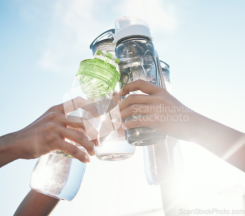 Image of Hands, water bottle and toast to fitness together after workout, exercise or training outdoor with team of players. Sport, goals and cheers with group and liquid for hydration, celebration and unity