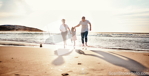 Image of Beach, sunset and child with her mother and father on a vacation, adventure or holiday together for bonding. Travel, having fun and girl kid walking with parents on the sand by ocean on weekend trip.