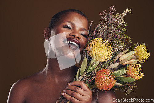 Image of Skincare, smile and protea with the face of a black woman in studio on brown background for natural treatment. Beauty, plant or cosmetics and a young model posing for aesthetic wellness with flowers