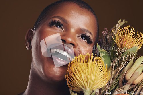 Image of Beauty, makeup and black woman with flowers in a studio for natural face cosmetics for self care. Happy, smile and young African model with protea floral aesthetic isolated by a brown background.