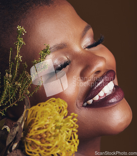 Image of Face, beauty and protea with the smile of a black woman in studio on brown background for natural treatment. Happy, plant or cosmetics and a young model indoor for aesthetic wellness with flowers