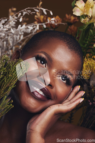 Image of Beauty, cosmetic and black woman with flowers in a studio for natural face makeup for cosmetology. Happy, smile and young African female model with floral aesthetic isolated by a brown background.