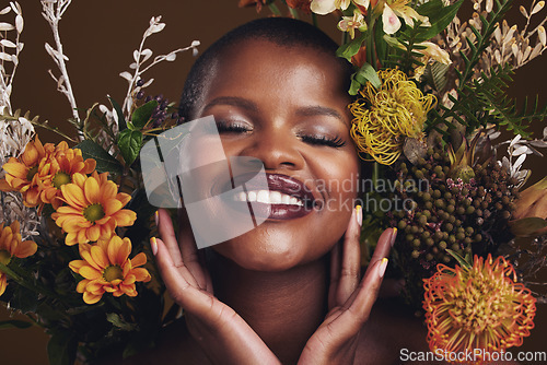 Image of Skincare, cosmetics and protea with the face of a black woman in studio on brown background for natural treatment. Smile, plant or beauty and a happy model for eco or aesthetic wellness with flowers