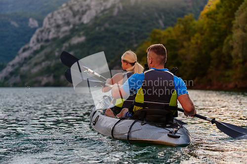 Image of A group of friends enjoying having fun and kayaking while exploring the calm river, surrounding forest and large natural river canyons