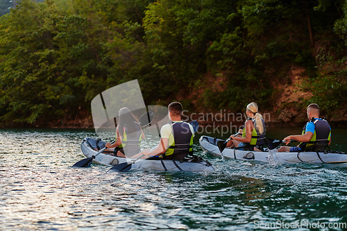 Image of A group of friends enjoying having fun and kayaking while exploring the calm river, surrounding forest and large natural river canyons