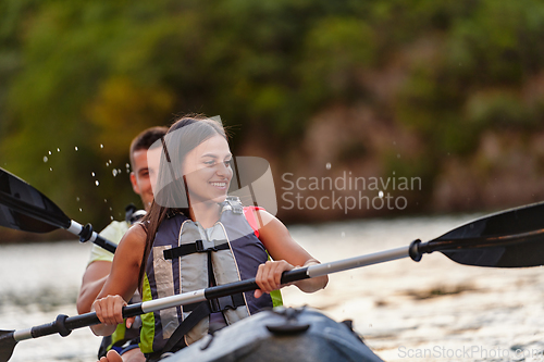 Image of A young couple enjoying an idyllic kayak ride in the middle of a beautiful river surrounded by forest greenery