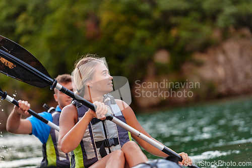 Image of A young couple enjoying an idyllic kayak ride in the middle of a beautiful river surrounded by forest greenery