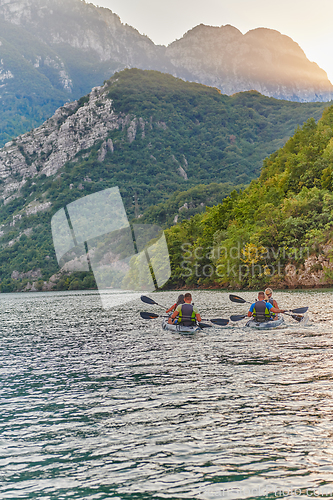 Image of A group of friends enjoying having fun and kayaking while exploring the calm river, surrounding forest and large natural river canyons