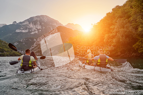 Image of A group of friends enjoying fun and kayaking exploring the calm river, surrounding forest and large natural river canyons during an idyllic sunset.