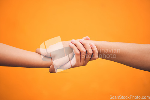 Image of Holding hands, studio and closeup for support, help and care for teamwork by orange background. People, friends and together for solidarity, link and connection with synergy, partnership and strong