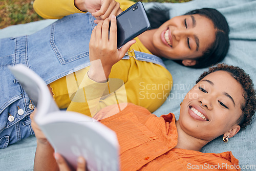 Image of Girl friends, park and top view with reading, book and smartphone for blog, relax or knowledge in nature. Gen z students, phone and story on blanket, picnic or outdoor for holiday, backyard or garden