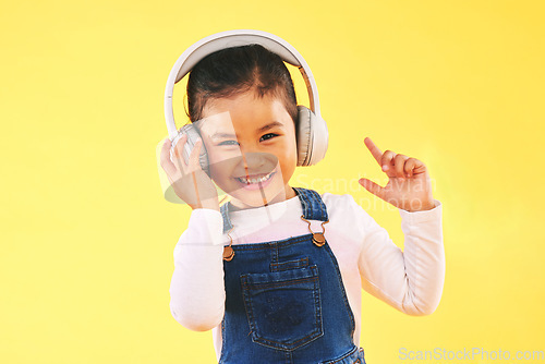 Image of Girl child, studio portrait and headphones with smile, listening or audio tech by yellow background. Happy female kid, sound and music with streaming subscription, radio and hearing in trendy fashion