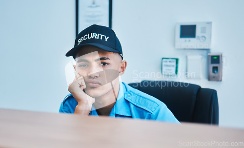 Image of Portrait, surveillance and a bored man security guard sitting at a desk in his office to serve and protect. CCTV, safety and control with a tired officer working as a private service employee