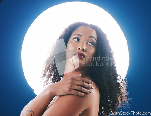 Image of Skincare, spotlight and face of woman with beauty for wellness, cosmetics and facial care in studio. Circle, creative salon and person for makeup, glamour and art deco aesthetic on blue background