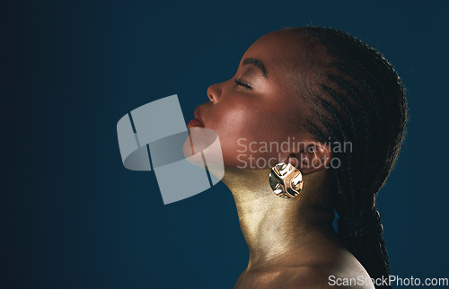 Image of Profile, beauty and black woman in gold for culture, heritage or tradition on a blue background in studio. Face, mockup and african style with a young model closeup for elegance or cosmetics