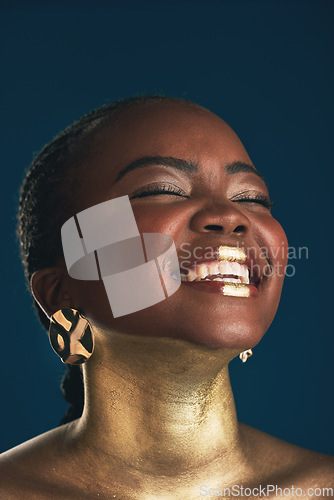 Image of Gold makeup, face and black woman laughing at funny creativity, facial cosmetics paint and beauty art design. African culture joke, comedy or glamour person with creative face glow on blue background