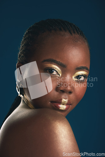 Image of Gold makeup, portrait and black woman confident with creative art, facial cosmetics paint and beauty design. African culture, studio or female model with face glow, shine or unique on blue background