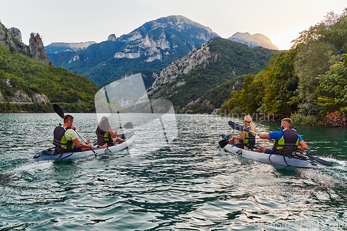 Image of A group of friends enjoying fun and kayaking exploring the calm river, surrounding forest and large natural river canyons during an idyllic sunset.