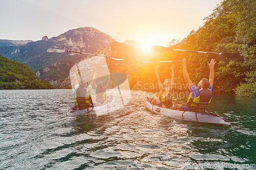 Image of A group of friends enjoying fun and kayaking exploring the calm river, surrounding forest and large natural river canyons during an idyllic sunset.