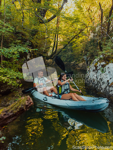 Image of A young couple enjoying an idyllic kayak ride in the middle of a beautiful river surrounded by forest greenery