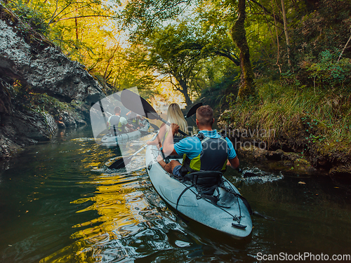 Image of A group of friends enjoying having fun and kayaking while exploring the calm river, surrounding forest and large natural river canyons