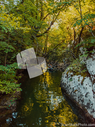 Image of A young couple enjoying an idyllic kayak ride in the middle of a beautiful river surrounded by forest greenery