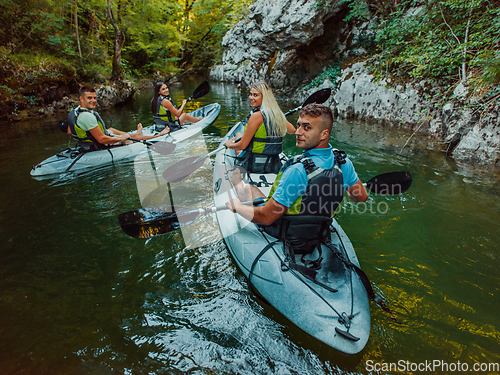 Image of A group of friends enjoying having fun and kayaking while exploring the calm river, surrounding forest and large natural river canyons