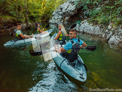 Image of A group of friends enjoying having fun and kayaking while exploring the calm river, surrounding forest and large natural river canyons