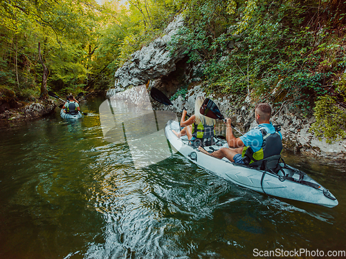 Image of A group of friends enjoying having fun and kayaking while exploring the calm river, surrounding forest and large natural river canyons