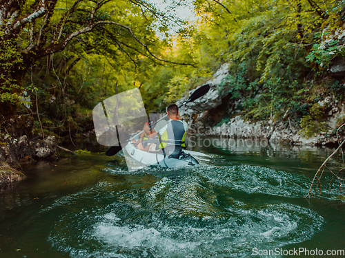 Image of A young couple enjoying an idyllic kayak ride in the middle of a beautiful river surrounded by forest greenery