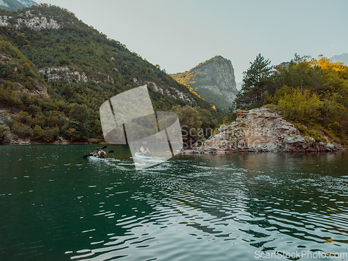 Image of A group of friends enjoying having fun and kayaking while exploring the calm river, surrounding forest and large natural river canyons