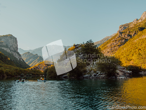 Image of A group of friends enjoying having fun and kayaking while exploring the calm river, surrounding forest and large natural river canyons