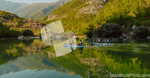 Image of A group of friends enjoying having fun and kayaking while exploring the calm river, surrounding forest and large natural river canyons