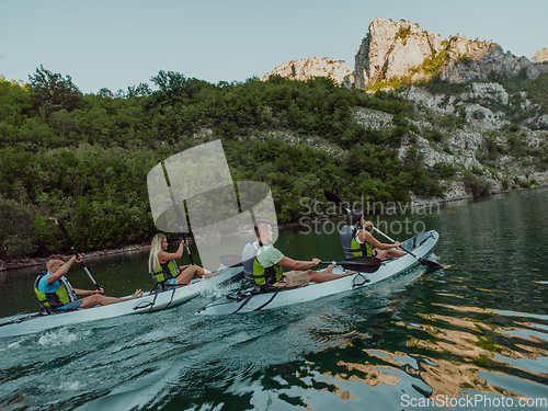 Image of A group of friends enjoying having fun and kayaking while exploring the calm river, surrounding forest and large natural river canyons